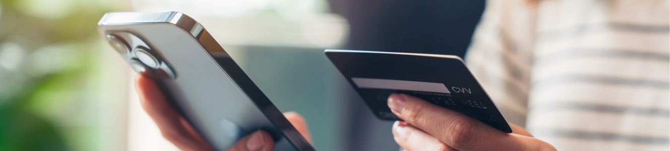 Woman holding a phone with a debit card. 