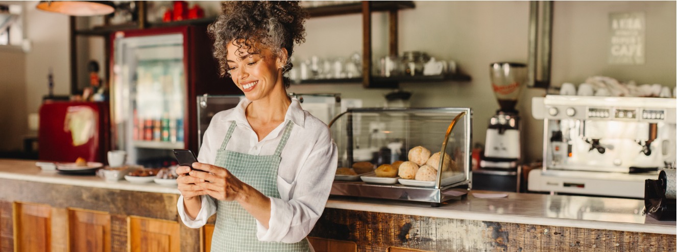 cafe owner using a smartphone in her shop picture