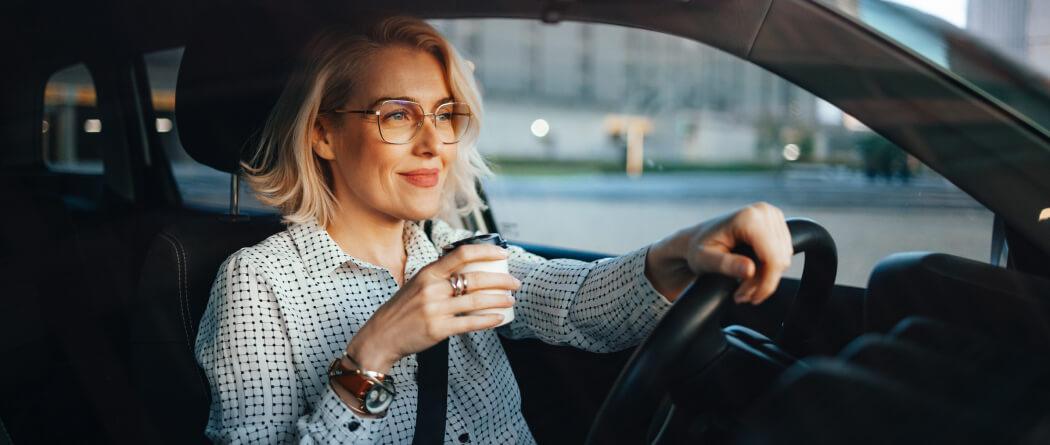 Young woman sitting in a car and holding a coffee cup